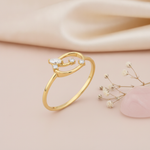 gold open loop ring with marquise and round stones displayed on pink satin with dried baby's breath and a pink stone