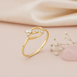 gold open loop ring with marquise and round stones displayed on pink satin with dried baby's breath and a pink stone
