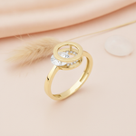 gold circular ring with a large round stone displayed on pink satin with dried grass and a small stone
