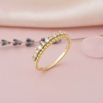 gold beaded row ring displayed on pink satin with a sprig of lavender and a pink stone