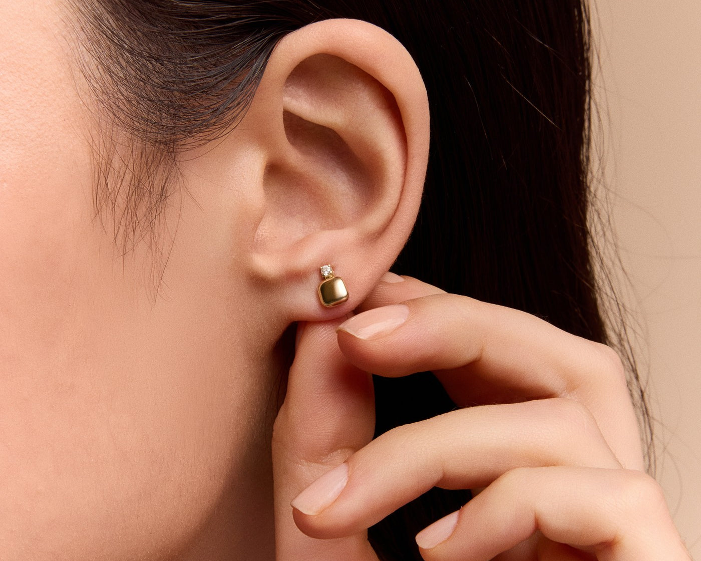 gold cushion stud earring on an ear